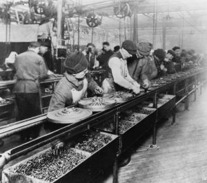 Workers on the first moving assembly line put together magnetos and flywheels for 1913 Ford autos" Highland Park, Michigan